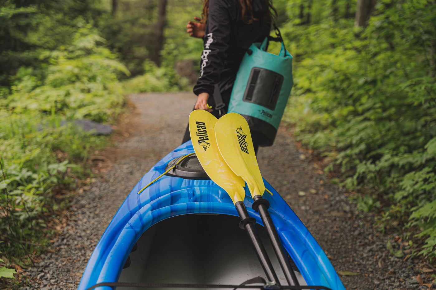 Pelican Argo 100X Kayak with a yellow paddle and a Pelican Exocool Dry bag